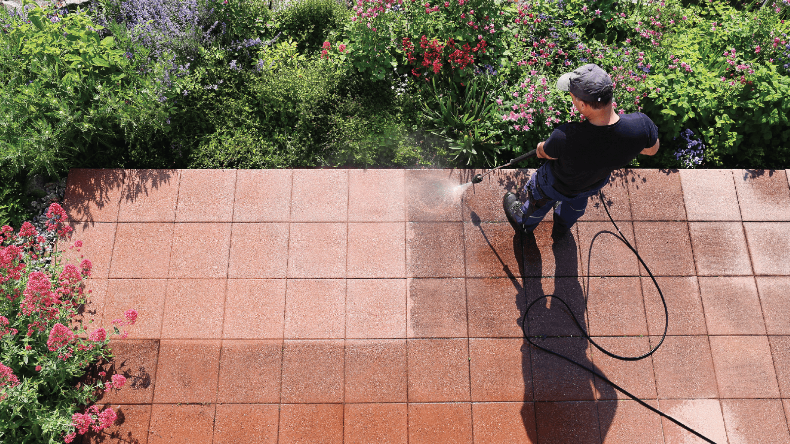 Technician rinsing a driveway with a surface cleaner